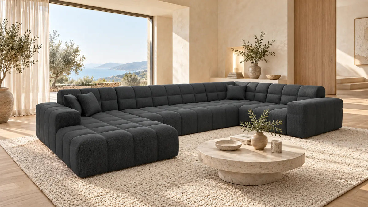 Dunkelgraue Ibiza Wohnlandschaft in U-Form in einem modernen Wohnzimmer mit Naturstein und hellem Holzboden